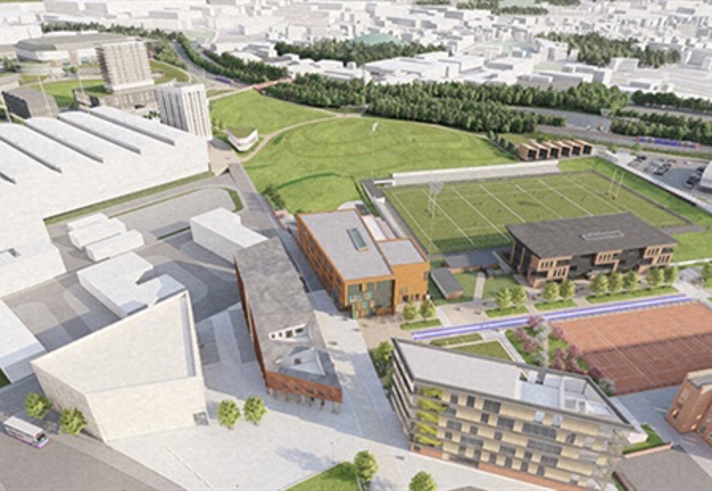 Group of seven people in a modern office lounge with colorful sofas and a wooden coffee table. A small plant sits on the table, and a large window behind them shows a brick building outside. A unique wooden bookshelf filled with books is visible on the left.