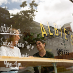 Two people sat in the window, drinking coffee, at Albie's Coffee.