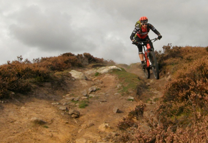 A person mountain biking up a steep hill in the countryside.