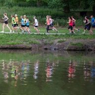 Group of runners participating in a park run alongside a lake.