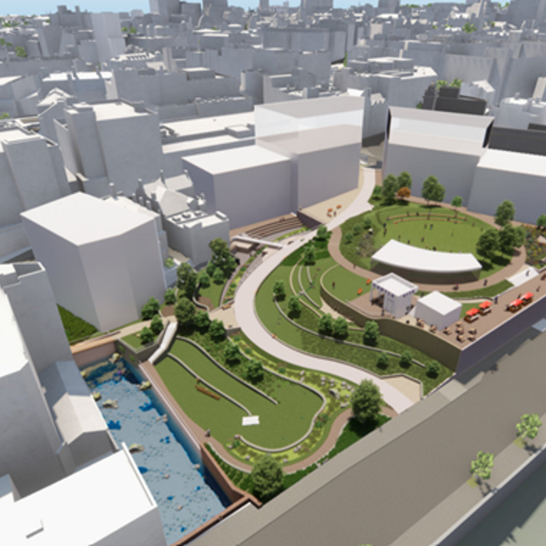 Digital rendering of an urban redevelopment project showing a landscaped green space surrounded by white building blocks. The design includes curved pathways, grassy areas, trees, and seating zones, with a central open space featuring a large canopy structure. On the right, there is a canal bordered by trees, and on the left, a blue climbing wall area. The surrounding city buildings are shown in simplified white models under bright daylight.