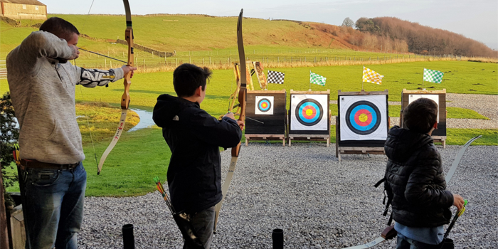 Three people doing archery at the Ringinglow Archery Target Sports Centre.