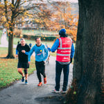 Two runners and a marshal at ParkRun in Hillsborough Park.
