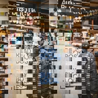 A man stands in a book shop, smiling at the camera.