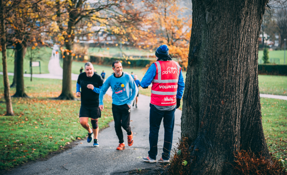 Two runners participating in a Hillsborough park run, talking to a park run volunteer.
