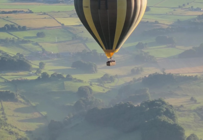 A hot air balloon flies over a scenic landscape.