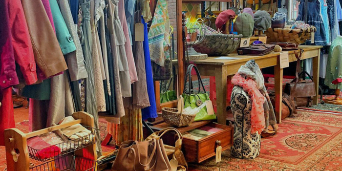 Inside The Warehouse with shelves and tables covered in things to buy and rails full of clothes.