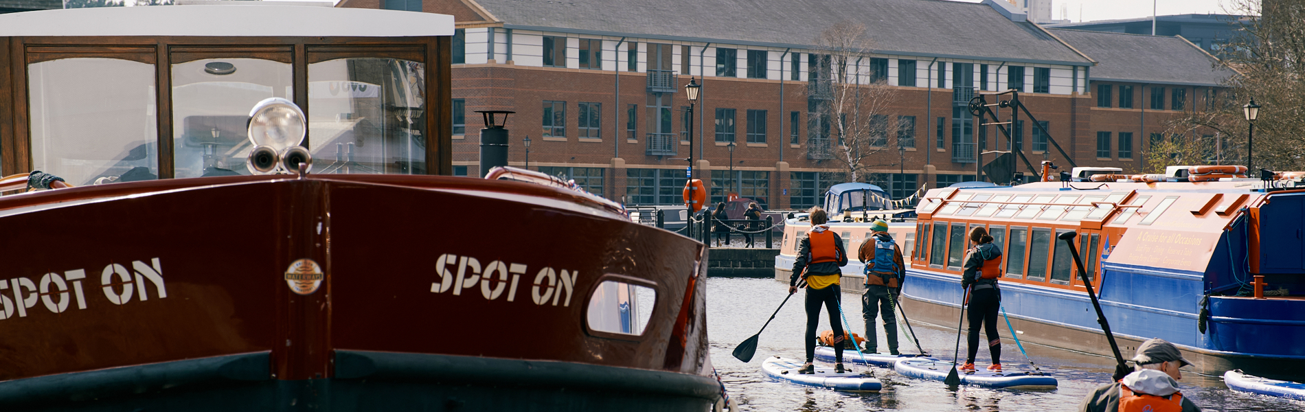 Four people stand up paddle boarding on the canal at Victoria Quays, Sheffield.