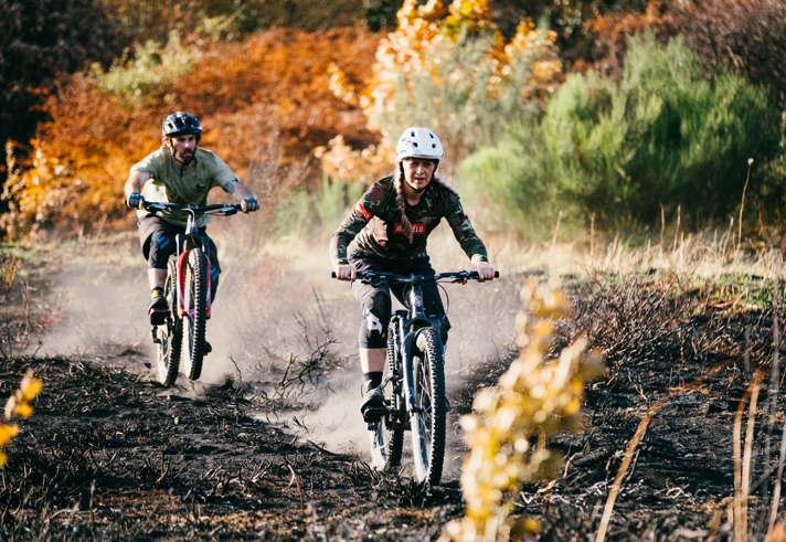 Two mountain bikers riding along a dirt track.