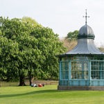 Weston Park bandstand with groups of people sat on the grass to the left.