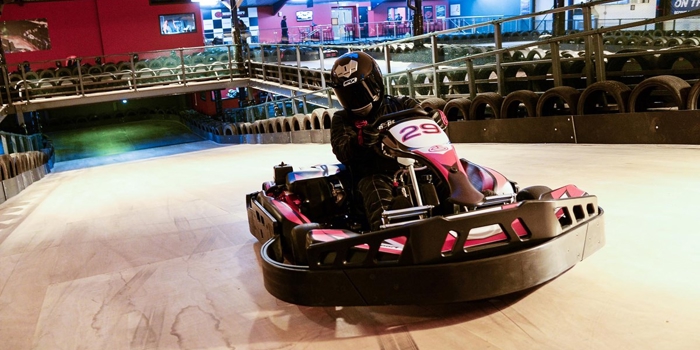 A person driving a go-cart on an indoor track.