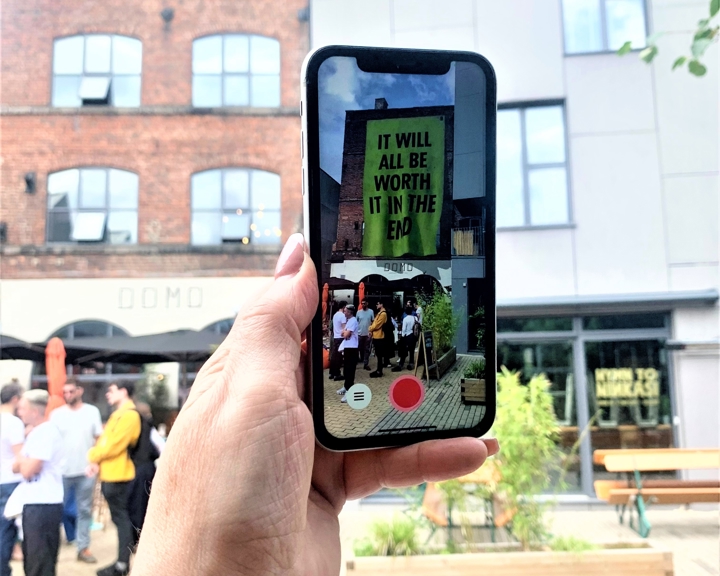  A hand holds up a mobile phone showing the Corbin Shaw artwork that is part of the Look Up! AR art trail in Sheffield.