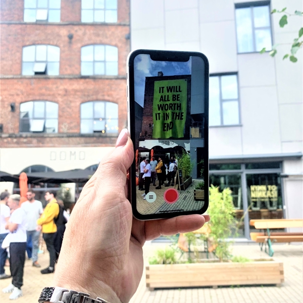  A hand holds up a mobile phone showing the Corbin Shaw artwork that is part of the Look Up! AR art trail in Sheffield.