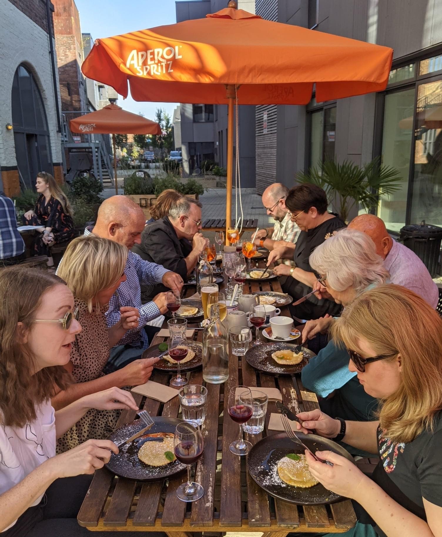 A small group of people are sat outside eating on the Kelham Island Food Tour.