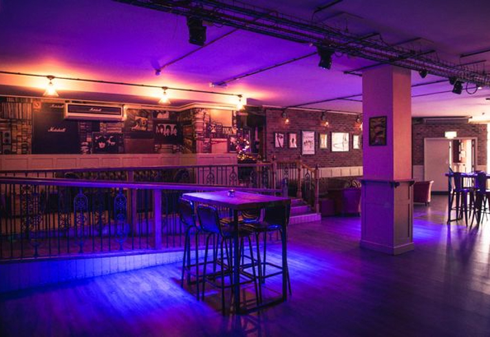 The dance floor and bar at Maida Vale, lit by purple lighting.