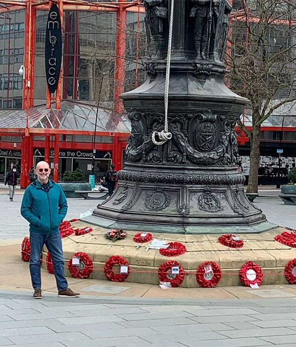 A man stands next to the War Memorial in Barkers Pool, Sheffield.