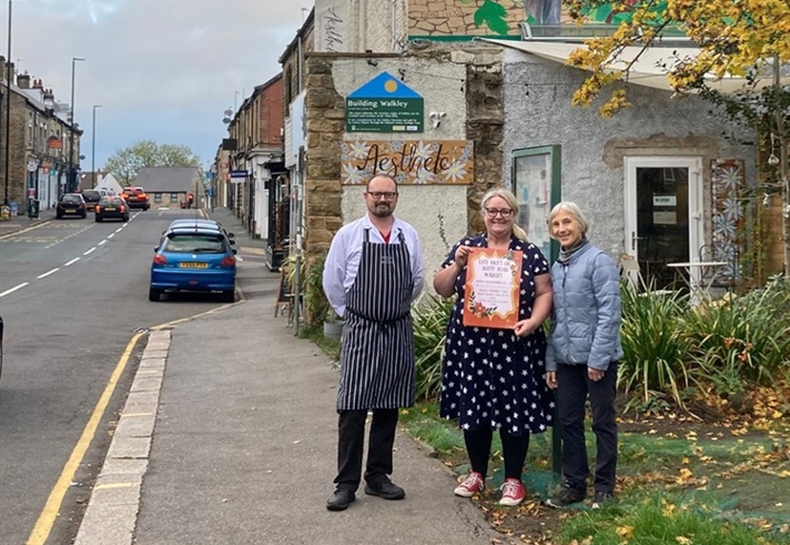 Three people stood on the pavement in an urban setting.