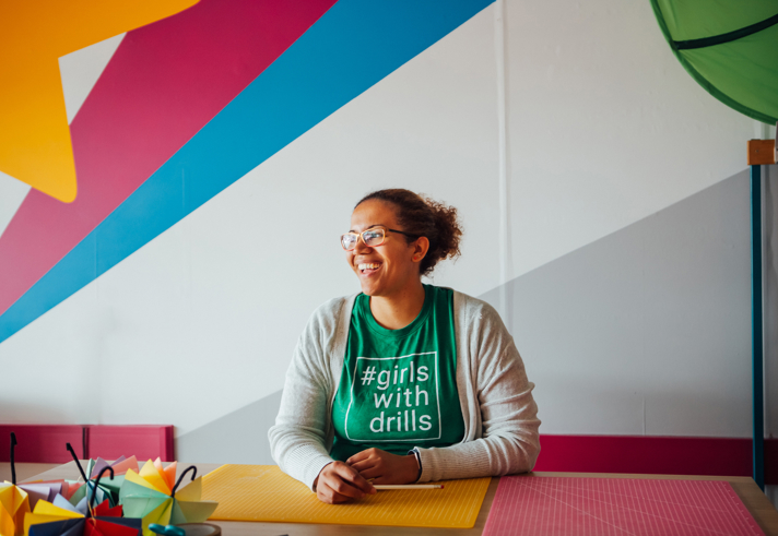 A photo of Kisha Bradley, Founder of Brightbox and Girls with Drills, sat at a desk.