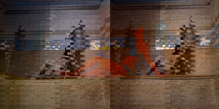 A woman soaking up the the heat of a sauna in Spa 1877