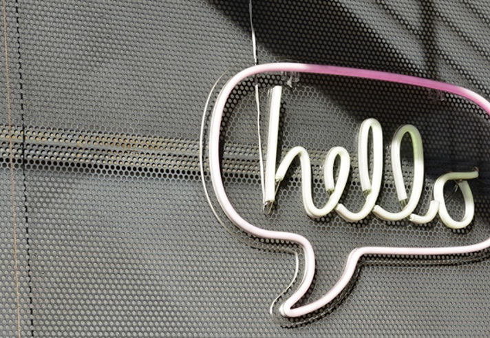 A neon sign on a wall that is a speech bubble with the word 'hello' in it.