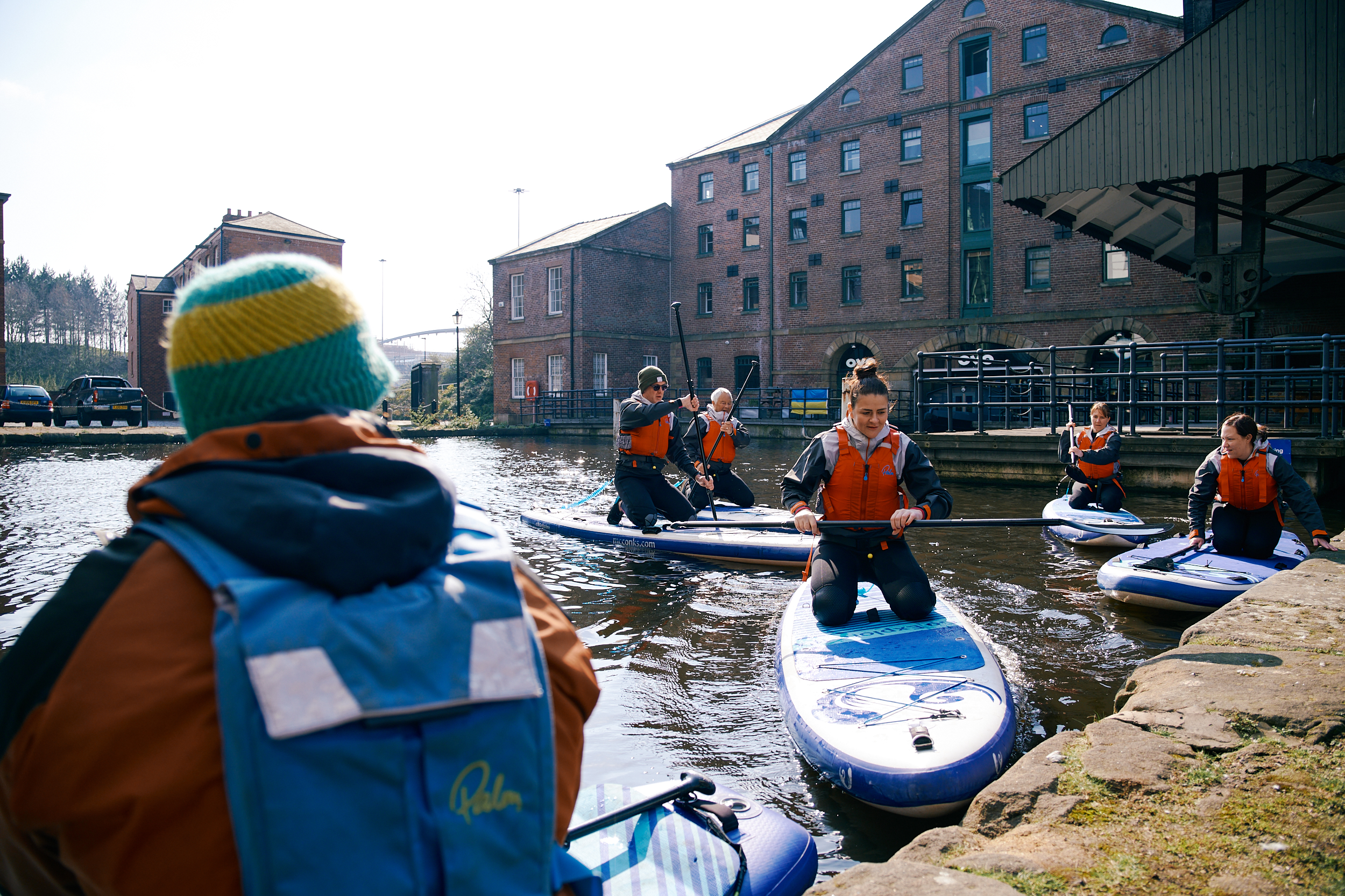 A group of people learning how to do stand-up paddle boarding at Victoria Quays in Sheffield city centre.