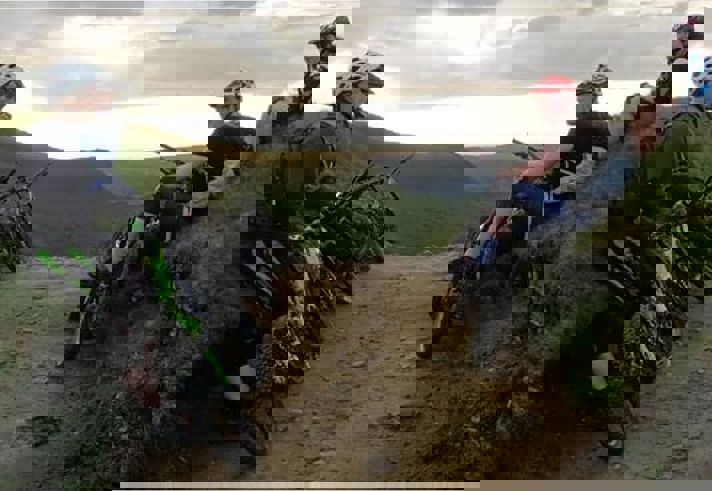 People mountain biking on a dirt track in the countryside.