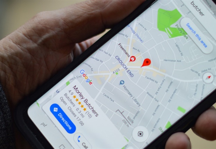 A stock image of a hand holding a mobile phone witha map app open on the screen.